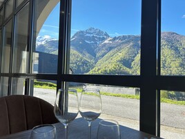 A table with wine glasses and a view of mountains through large windows.