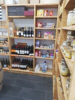 A store with shelves stocked with various products including wine bottles, canned goods, and household items.