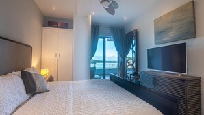 A hotel room with a large bed, a flat-screen TV, a ceiling fan, and a balcony with a view. - K & E Lemon Drop Cove (Cupecoy)