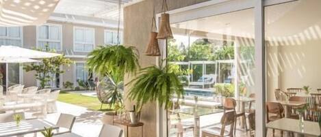 Un patio al aire libre con mesas y sillas, una sombrilla grande y plantas en macetas.