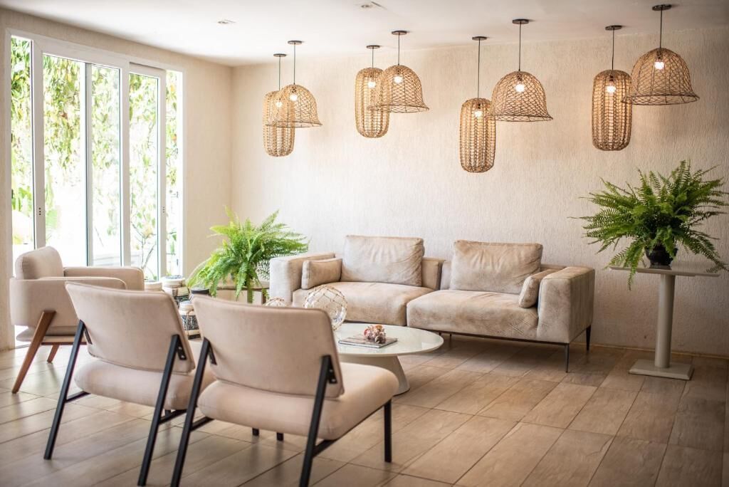 Uma sala de estar moderna com sofá, cadeiras, mesa de centro e luminárias de vime suspensas.