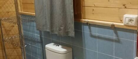 A bathroom with a toilet, bidet, and a metal shelf unit.