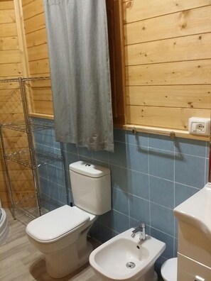 A bathroom with a toilet, bidet, and a metal shelf unit. - Camping Dal Pino (Massa)