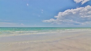 Uma praia com céu claro e águas calmas.