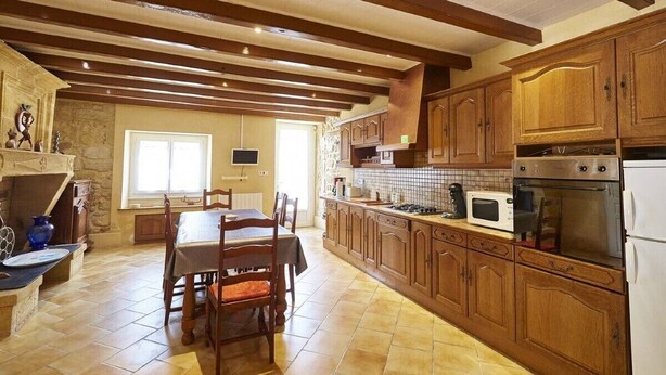 Una cocina amplia con armarios de madera, una mesa de comedor y una chimenea de piedra.