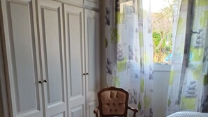 Un dormitorio con dos camas, un armario y una silla.