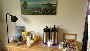 A breakfast setup with a coffee maker, milk jug, and containers of food on a wooden table. - Suður-Bár Guesthouse (Grundarfjörður)