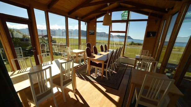 A wooden dining area with a view of mountains and a lake. - Suður-Bár Guesthouse (Grundarfjörður)