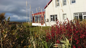A white building with a red roof and a glass structure. - Suður-Bár Guesthouse (Grundarfjörður)