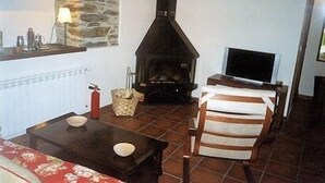 Een woonkamer met een stenen muur, open haard, televisie en een gestreepte stoel.