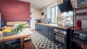 Une cuisine moderne avec des meubles de couleur sombre, un plan de travail en bois et un revêtement mural à motifs.