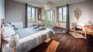 Une chambre moderne avec un grand lit, un plancher en bois, un bureau et une vue sur l’extérieur.