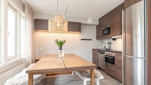 A modern kitchen with a wooden table, white chairs, a hanging light fixture, and built-in appliances. - Åre Travel- Mitt i Åre 2 (Are)