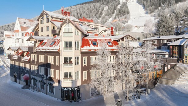 A hotel with a central tower, multiple stories, and a ski slope in the background. - Åre Travel- Mitt i Åre 2 (Are)
