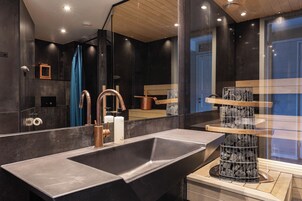 Un baño moderno con un lavamanos grande, un espejo y una original decoración de rocas.