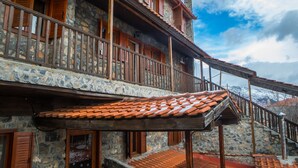 A stone building with wooden balconies and a tiled roof. - Exohiko Palaios Agios Athanasios (Edessa)