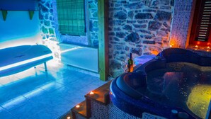 A spa area with a massage table, a hot tub, and stone walls. - Exohiko Palaios Agios Athanasios (Edessa)