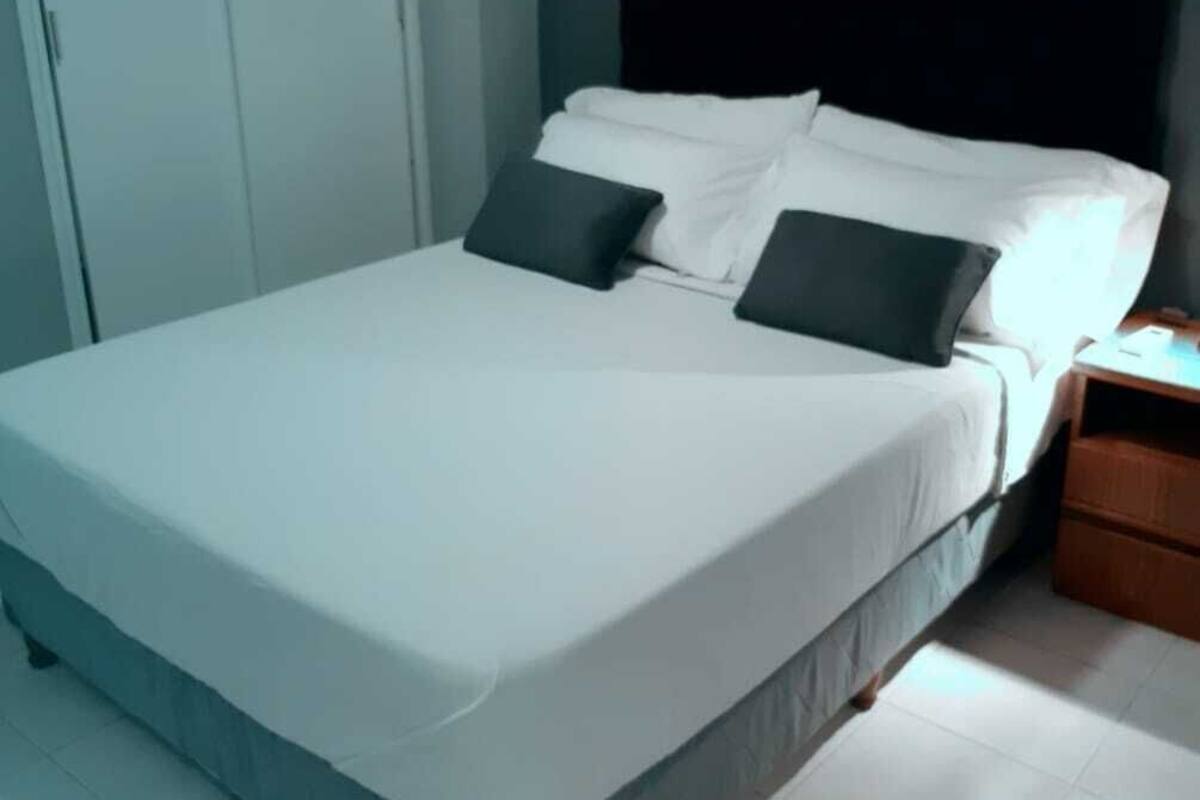 A bedroom with a bed, a nightstand, and a wardrobe.