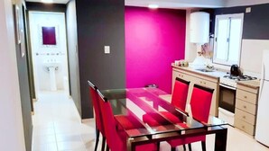 A dining area with a glass table and red chairs, a kitchen with a gas stove, and a bathroom with a white sink.