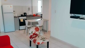 A compact living space with a kitchenette, a dining area, and a TV mounted on the wall.