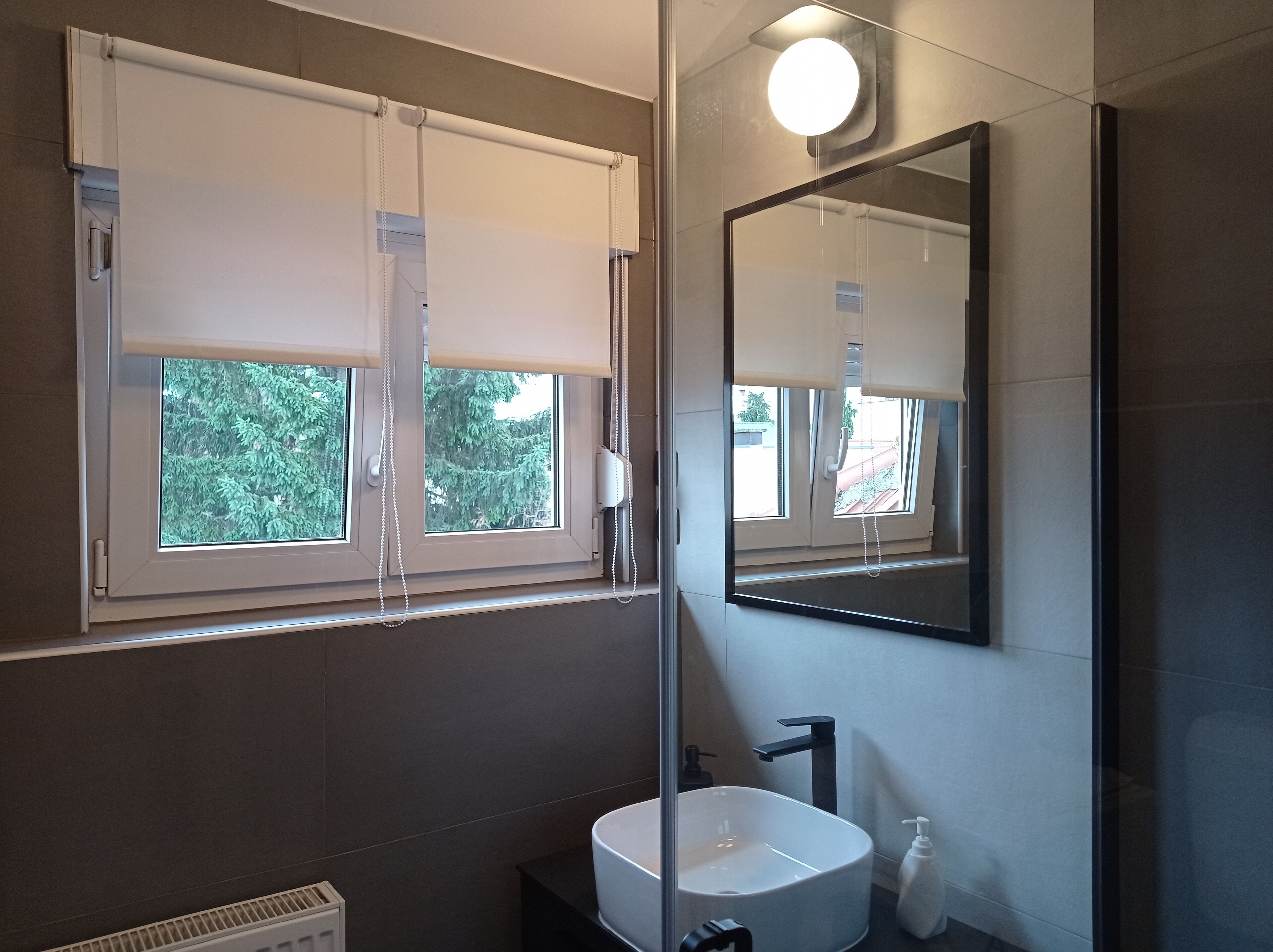 A bathroom with a large window, a sink, and a mirror.