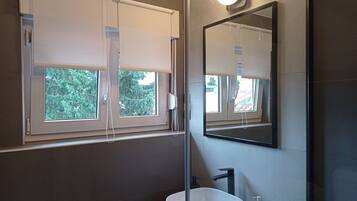 A bathroom with a large window, a sink, and a mirror.