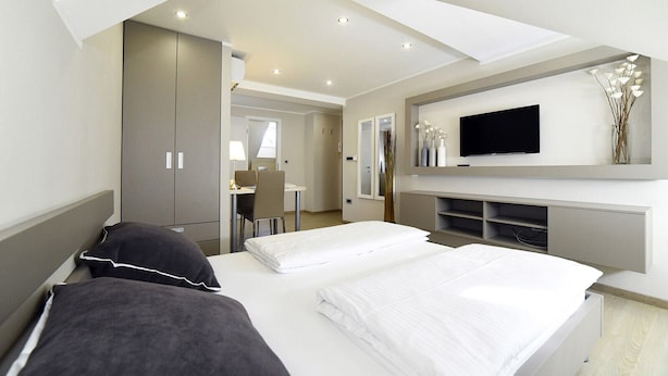 A modern hotel room with a large bed, a desk, and a TV mounted on the wall. - D&G Apartments Zagreb  (Zagreb)