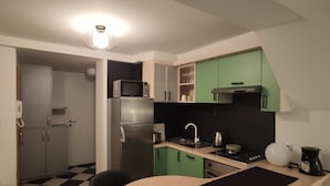 A compact kitchen with a refrigerator, microwave, sink, and a small dining area with a table and chairs. - D&G Apartments Zagreb  (Zagreb)