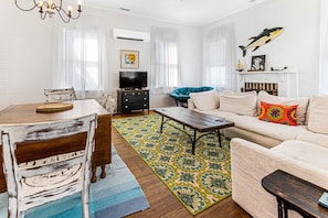 Relax in this stylish living room with a sofa, dining table, and television.