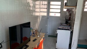 Eine kleine Küche mit Essecke, Fernseher und Kühlschrank.