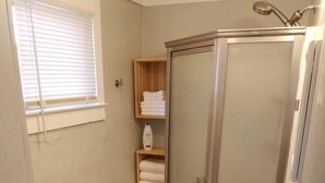 Et lille badeværelse med toilet, håndvask og bruser.