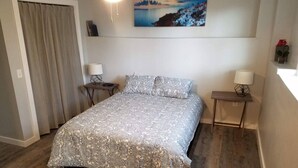 Et soveværelse med en seng, to sengeborde, et natbord, et maleri på væggen og et vindue med gardiner.