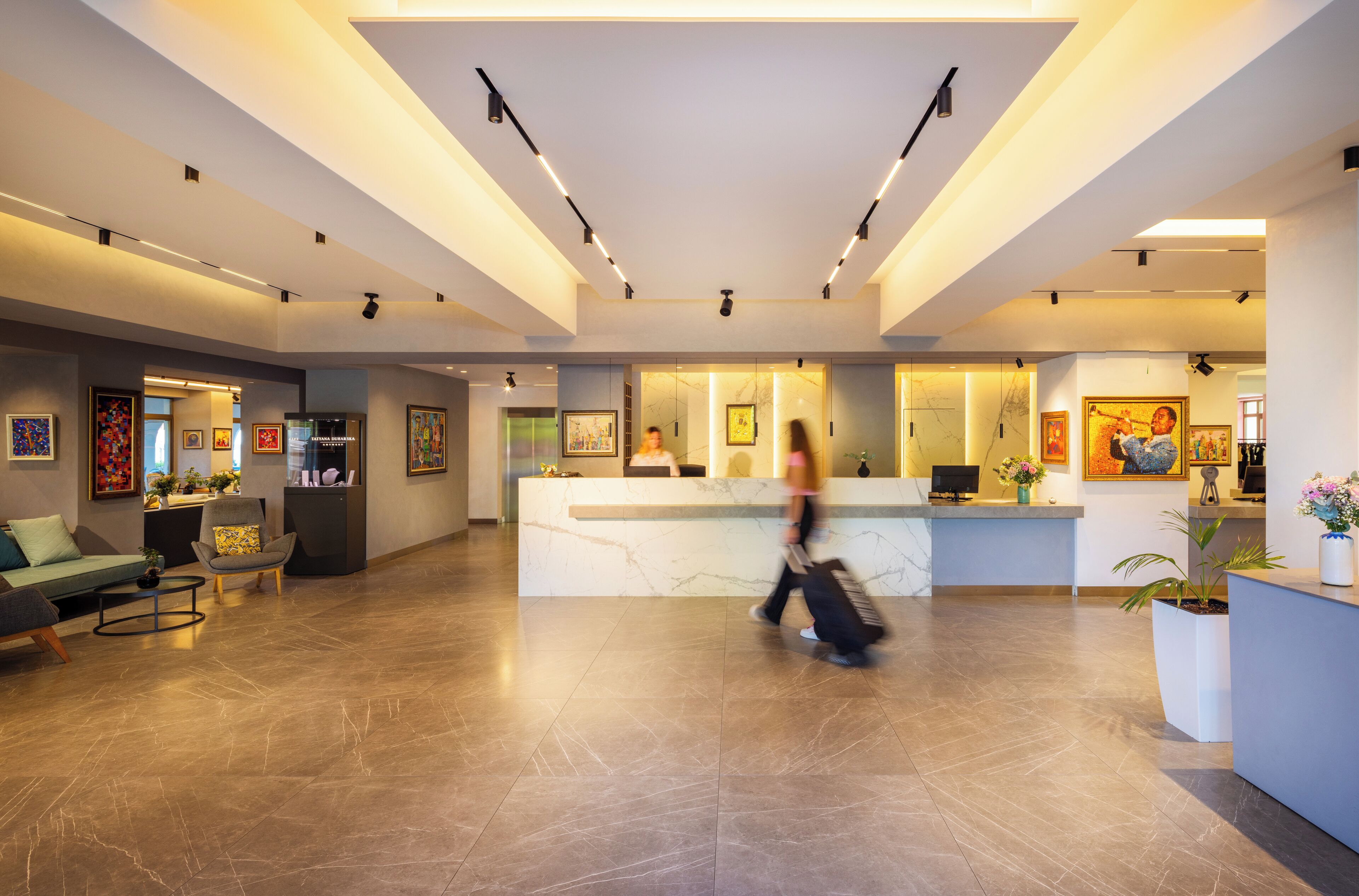 A spacious lobby with a reception desk, seating area, and artwork on the walls.