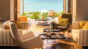 Una sala de estar moderna con vista al mar, que incluye sofás a rayas, una mesa de centro y un ventanal grande.