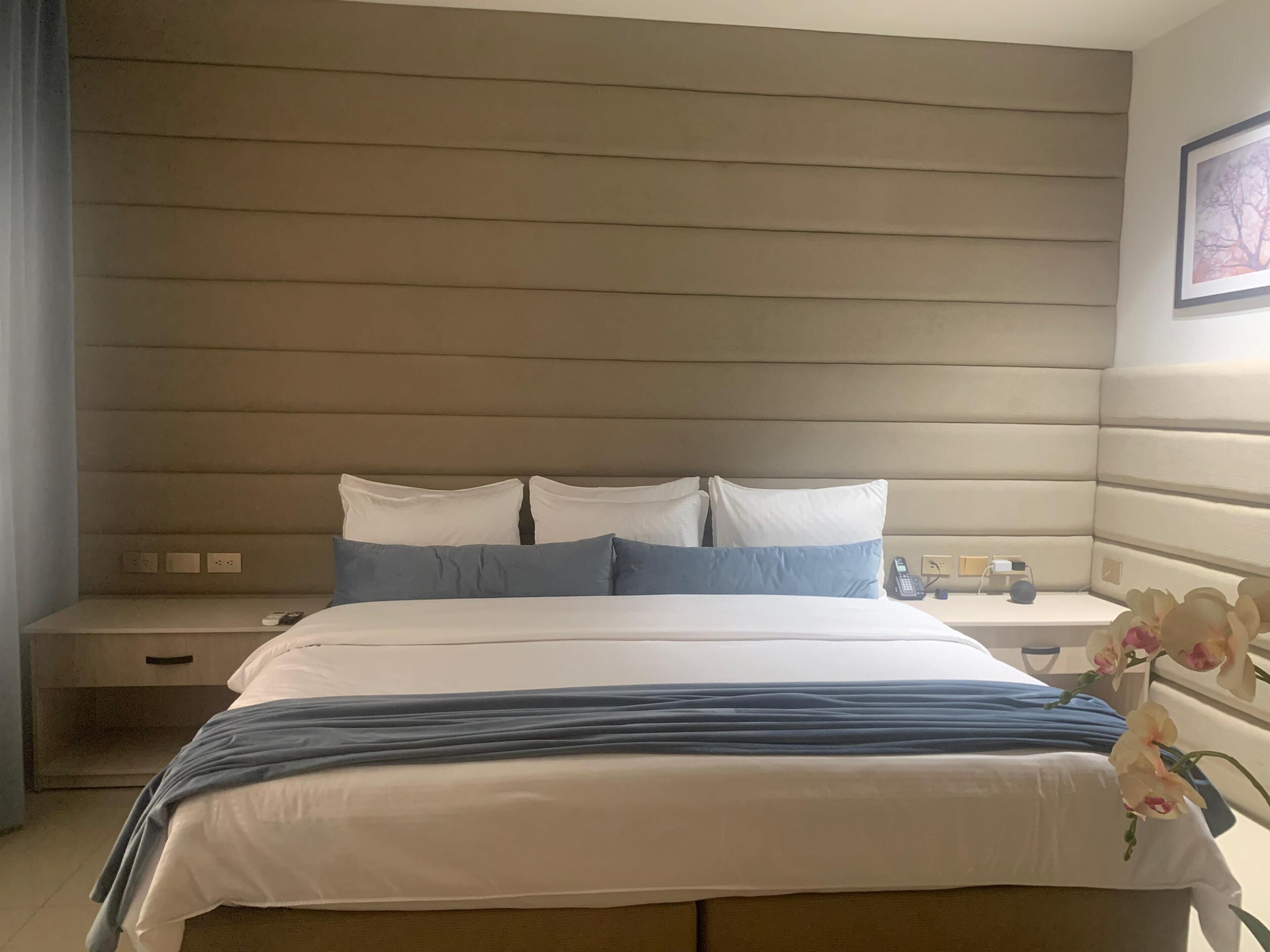 A hotel room with a large bed, a bedside table, and a nightstand.