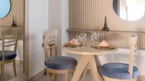 Comedor con una mesa redonda, cuatro sillas, un espejo y un panel en la pared.