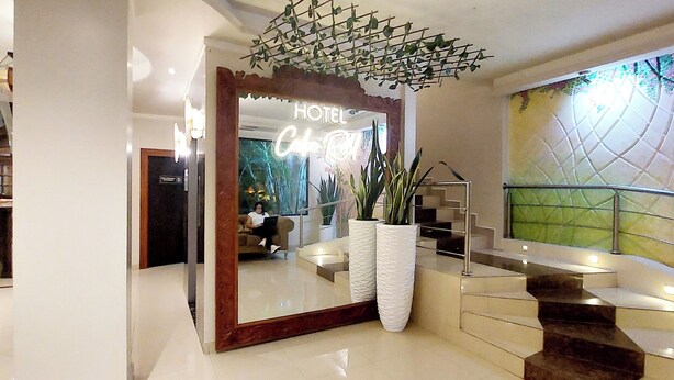 Un vestíbulo de hotel con un espejo grande, una escalera y un arreglo de plantas decorativas.