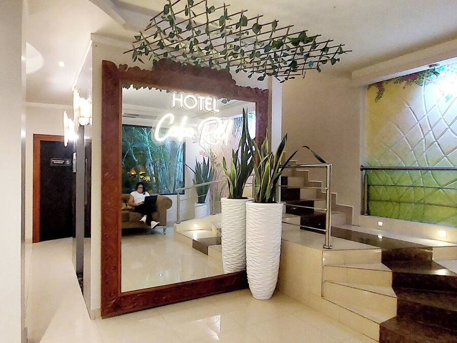Un vestíbulo de hotel con un espejo grande, una escalera y un arreglo de plantas decorativas.