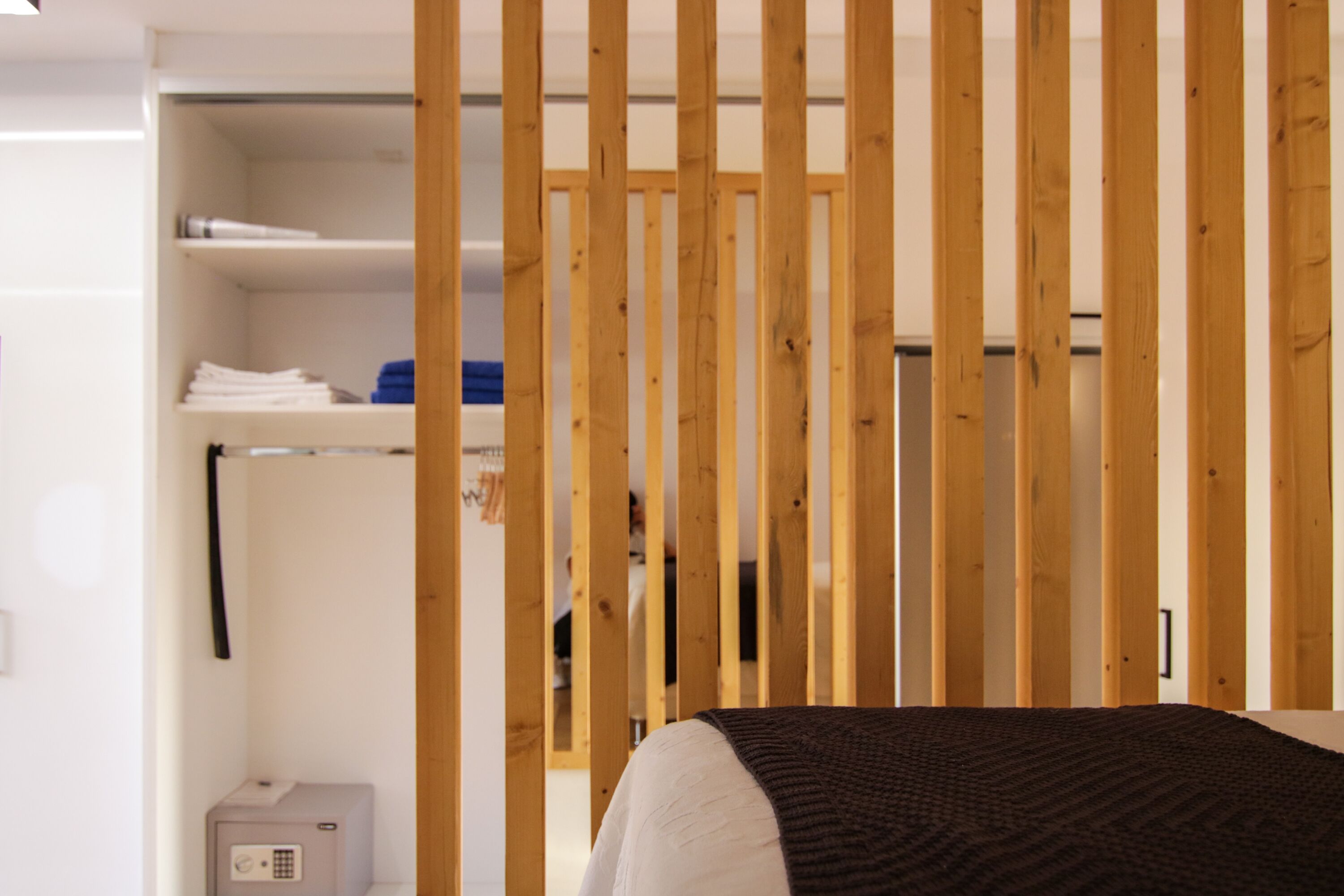 Een slaapkamer met een bed, houten latten, een kledingkast en een kluis.
