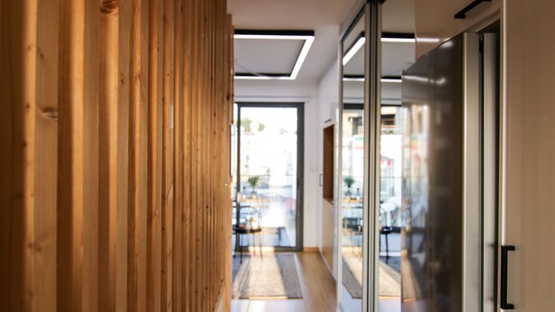 A modern interior with a wooden partition, a glass door, and a visible outdoor area through the glass. - Phaedrus Living: Seaside Luxury Flat Athina 109 (Paphos)