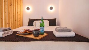 A neatly made bed with a wooden headboard, a bedside table with a bottle of water, a mug, and a plate of food. - Phaedrus Living: Seaside Luxury Flat Athina 109 (Paphos)