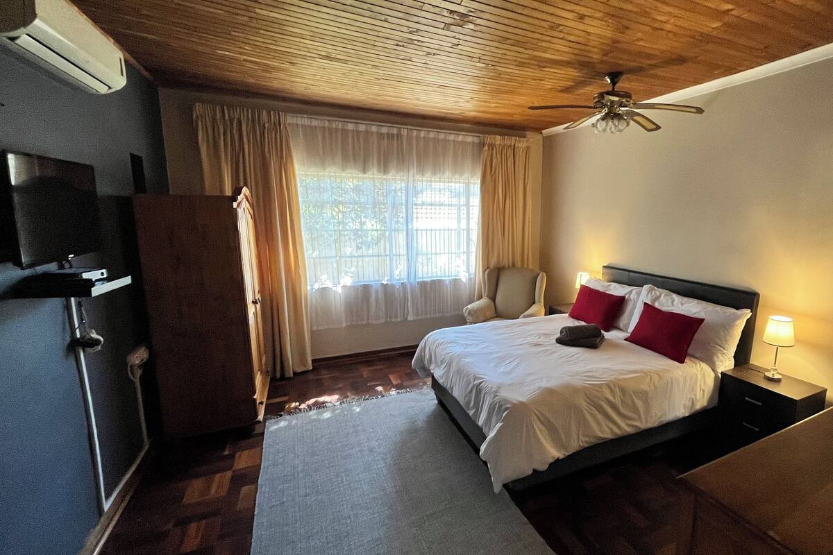 A hotel room with a bed, a desk, a chair, a TV, and a ceiling fan.