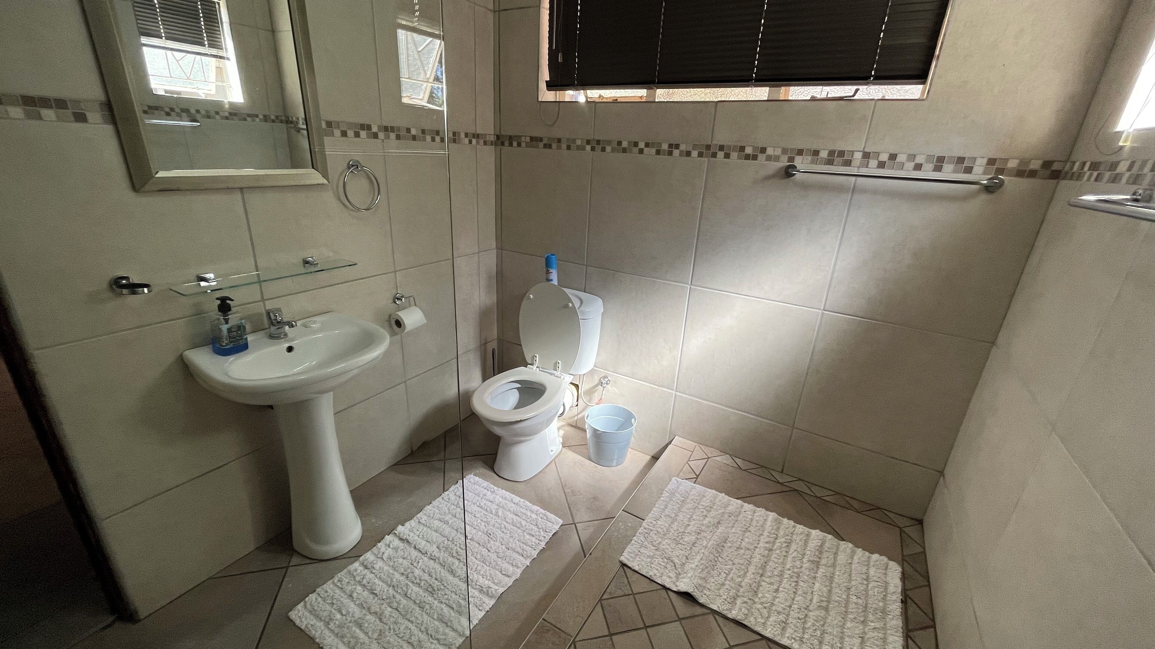Un bagno con lavandino, wc e bidet, pareti piastrellate e una finestra con persiane.