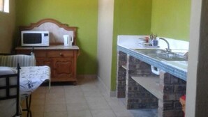 A compact kitchen with a microwave, a sink, and a dining area with a table and chairs. - Tumbleweeds (Chartwell)