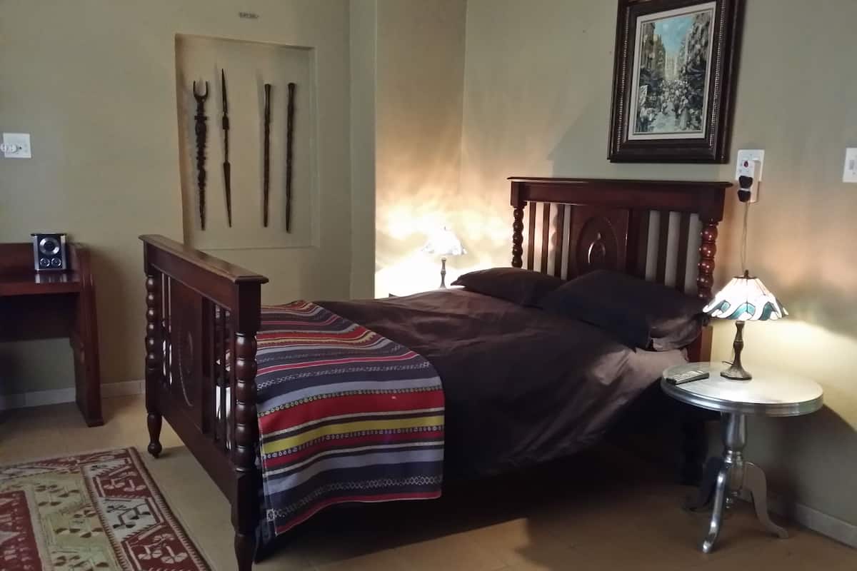Une chambre à coucher avec un lit en bois, une table de chevet avec une lampe, un tapis et un tableau encadré au mur.