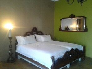 A neatly made bed with white linens, a wooden headboard, and a bedside table with a candle. - Tumbleweeds (Chartwell)