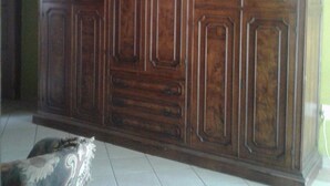 A large wooden wardrobe with multiple doors and drawers, positioned against a green wall. - Tumbleweeds (Chartwell)