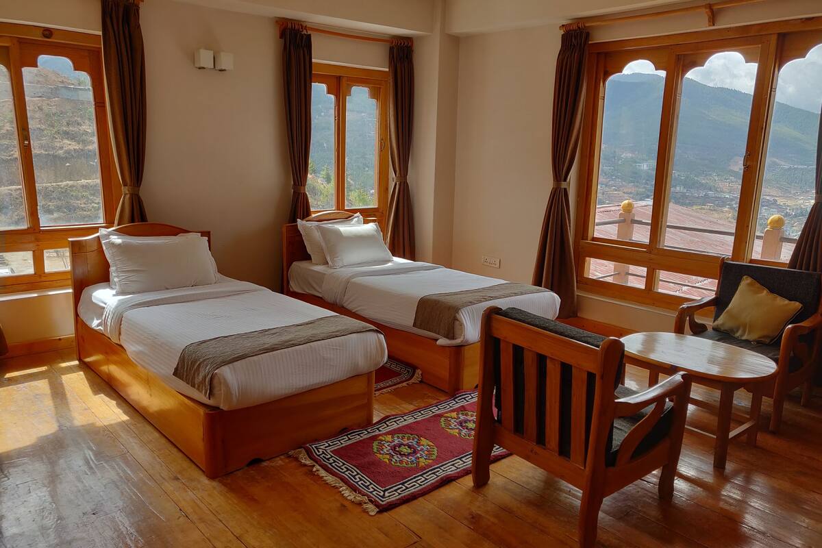 A room with two wooden beds, a small table, and a chair.
