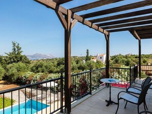 A covered outdoor area with a pool, chairs, and a view of the landscape. - Villa Pyramus (Apokoronas)