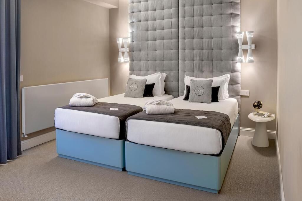 A hotel room with a large bed, two bedside tables, and a wall-mounted light fixture.